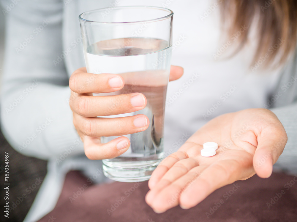 Closeup woman hand with pills medicine tablets and glass of water for headache treatment. Healthcare, medical supplements concept - obrazy, fototapety, plakaty 