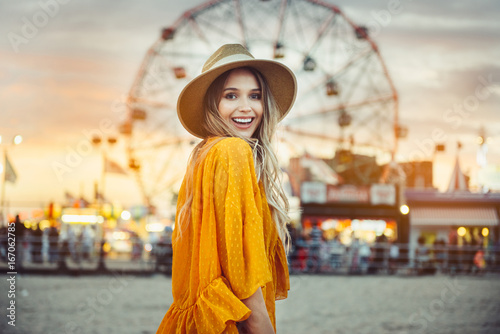 Poster Beautiful exited smiling tourist woman having fun at amusement park at hot summer day trip on the beach