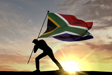 Wall Mural - South Africa flag being pushed into the ground by a male silhouette. 3D Rendering