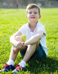 boy in shirt sitting on the grass