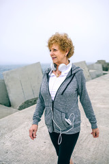 Wall Mural - Senior sportswoman walking by sea concrete pier