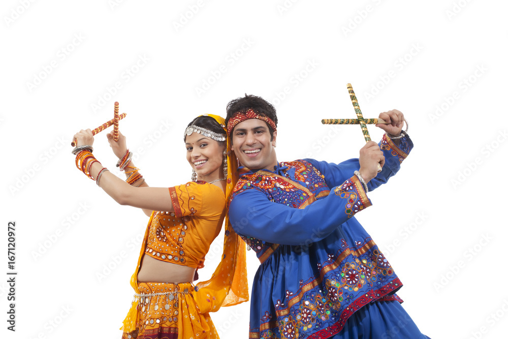 Portrait of happy young couple in traditional wear standing back to ...
