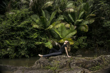 Side View Of Woman Relaxing On Rocks At Lakeshore In El Yunque National Forest