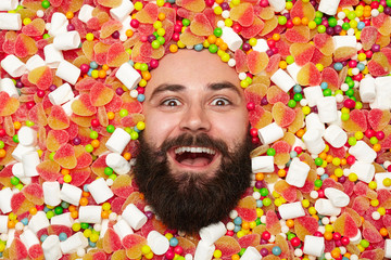 Excited bearded man in sweets assortment