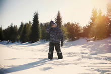 Boy Standing On Snow Covered Field Against Sky During Sunset