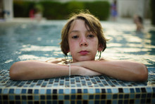 Portrait Of Boy Leaning On Edge Of Swimming Pool