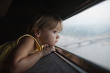 Side View Of Thoughtful Girl Looking Through Window