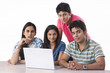 © IndiaPix - Portrait of confident college students with laptop in library