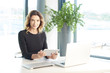 © sepy - Businesswoman portrait. Portrait of a smiling financial assistant working on laptop at the office.