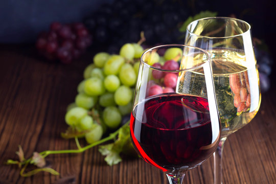 Fototapete - Glasses with red and white wine with grapes on wooden background