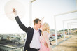 © olegparylyak - Pretty sunny outdoor portrait of young stylish couple while kissing on the roof with city view