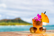 Hawaii mai tai cocktail drink on waikiki beach bar with flower, pineapple and sunglasses. View of the ocean and diamond head mountain in Honolulu, Hawaii. Summer vacation.