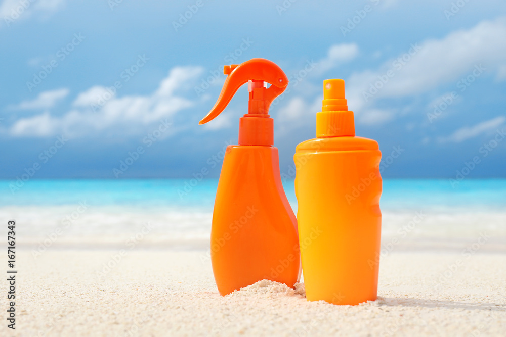 Bottles with sunscreen cream on sea shore. Summer vacation concept