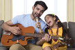 © IndiaPix - Father and daughter singing while playing guitar