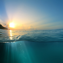 Beautiful sky with the sun image splitted by waterline. Air bubbles and sunrays underwater