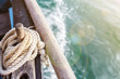 rope wound on a wooden cleat fixed on the mast of a vintage sailing boat with a blur background
