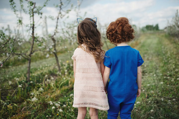 Wall Mural - little boy and girl in blooming garden