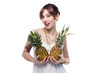 © LIGHTFIELD STUDIOS - sensual young woman holding ripe pineapples and looking at camera isolated on white