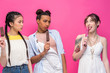 © LIGHTFIELD STUDIOS - jealous young women holding ice creams and looking at friend licking ice cream isolated on pink