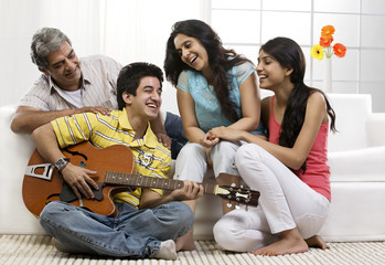 Boy playing the guitar for his family 