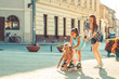 Mother plays with her daughters on the street in the neighborhood. They drive rollerblades. Family concept.	