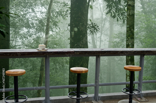 Plakat kawiarnia w lesie mgły i filiżankę kawy na drewnianym stole