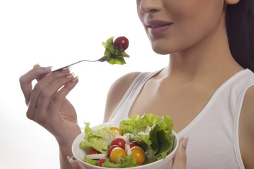 Mid section of woman eating salad of lettuce, cherry tomatoes and mushrooms isolated over white background 