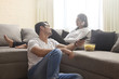 © IndiaPix - Young man watching TV while woman listening music sitting on sofa