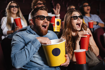 laughing friends sitting in cinema watch film