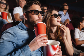 Sticker - Concentrated loving couple friends sitting in cinema