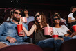 © Drobot Dean - Hhappy friends sitting in cinema watch film eating popcorn
