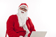 © IndiaPix - Happy Santa Claus listening to music with eyes closed with laptop over white background