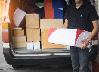 Smiling young male postal delivery courier man in front of cargo van delivering package