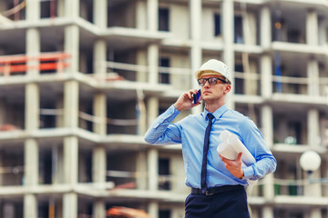 Wall Mural - Construction engineer at the construction site looking at the camera and talking mobilephone