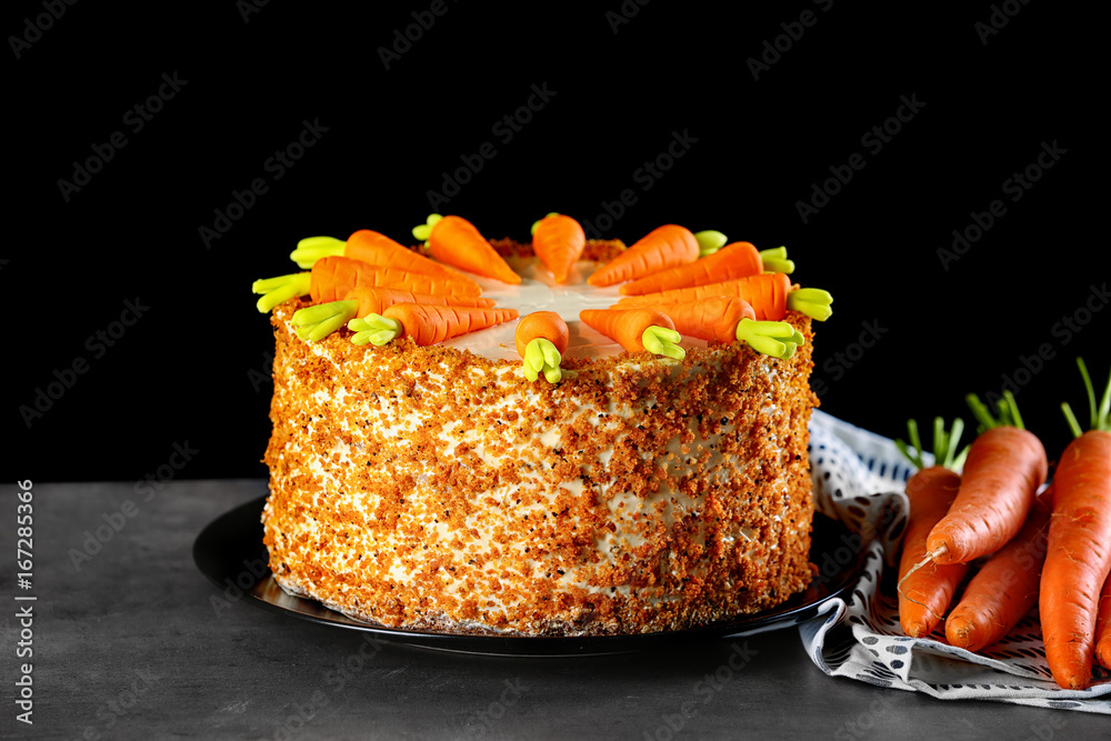 Plate with delicious carrot cake on black background