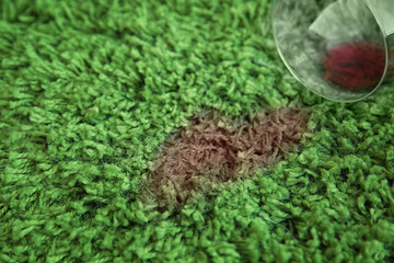 Wall Mural - Glass of red wine spilled on green carpet, close up