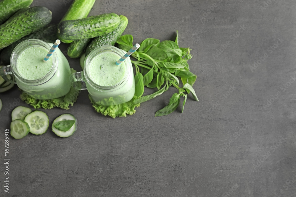 Mason jars with fresh smoothie and vegetables on grey background