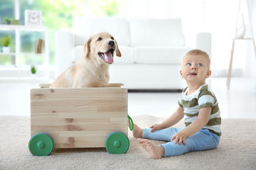 Wall Mural - Cute child and Labrador Retriever playing with wooden toy cart at home