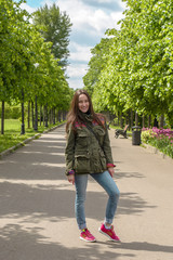 Wall Mural - Happy young woman in sports clothing walking in summer Park