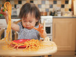 baby girl eating messy spaghetti at home