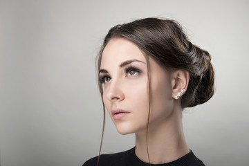 Portrait of young brunette woman with clean skin and daily makeup and hairdo bun on an isolated background