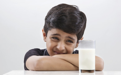 Wall Mural - Young boy looking at a glass of milk 