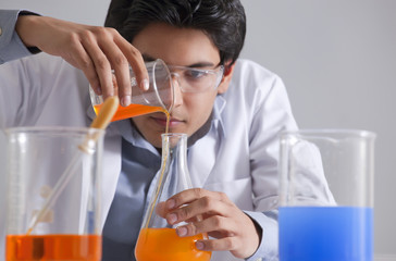 Young scientist pouring liquid into flask 