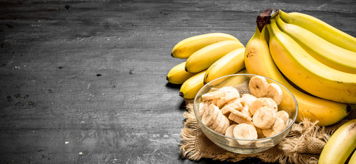 Canvas Print - Ripe bananas with pieces of sliced bananas in a bowl .