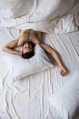 Wall Mural - top view of handsome shirtless bearded man sleeping in bed under white blanket