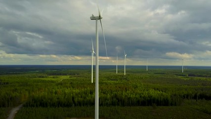 Wall Mural - Wind turbines on forest on cloudy day, 4K aerial video. 