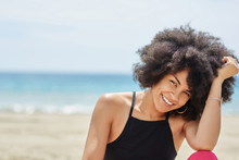 Pretty Afro American Woman On Beach Propping Head On Hand Smiling
