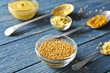 Delicious mustard seeds in bowl on wooden table