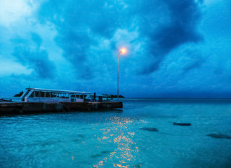 Canvas Print - View of boat near sea coast at resort in evening