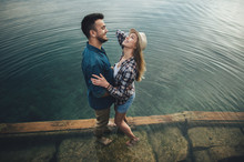 Young Couple Of Tourists In Love Standing On A Wooden Pier